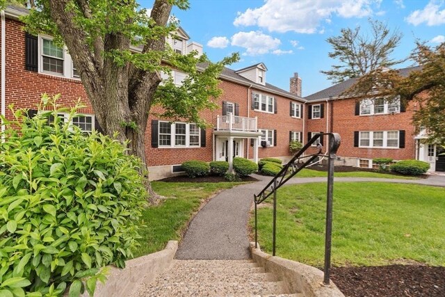 74 Boylston St Unit 2, Newton, MA 02467 - view of front facade featuring brick siding, a front yard, a chimney, and a balcony