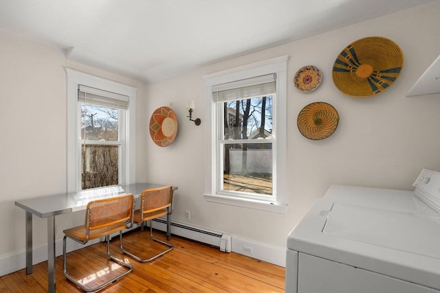 dining space with a baseboard heating unit, a healthy amount of sunlight, and light wood-style floors