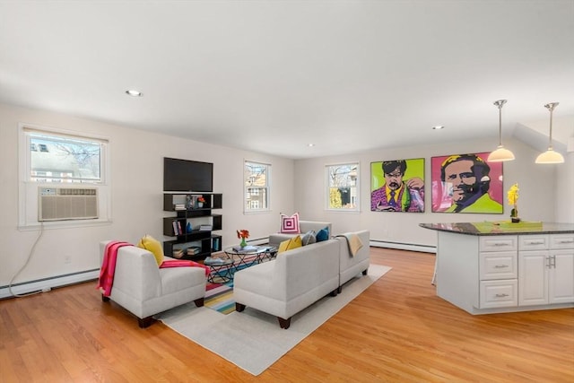 living area with light wood-style floors, baseboard heating, and a wealth of natural light