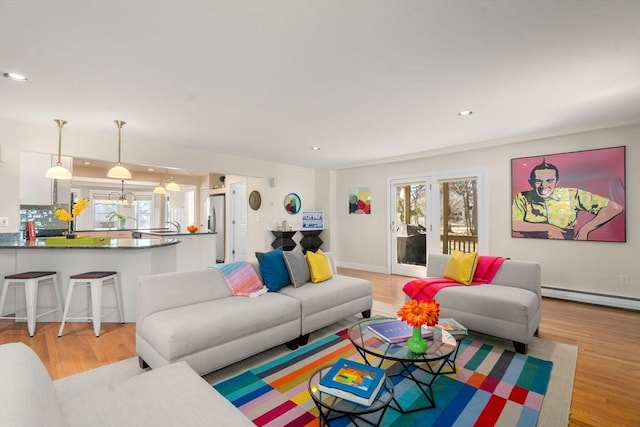 living room featuring plenty of natural light, light wood-style flooring, and baseboard heating