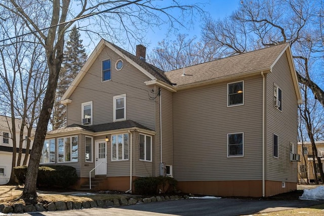 view of property exterior with entry steps, a shingled roof, and a chimney