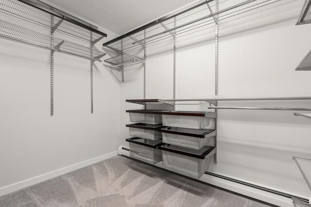 walk in closet featuring a baseboard heating unit and carpet