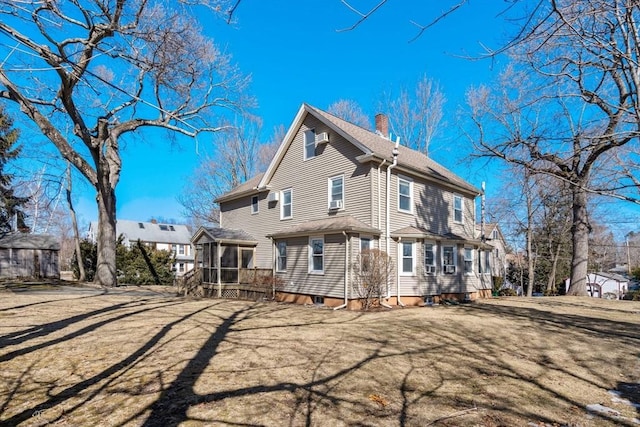 rear view of property featuring a sunroom and a chimney