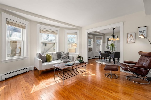 sitting room with a baseboard heating unit, light wood finished floors, and a chandelier