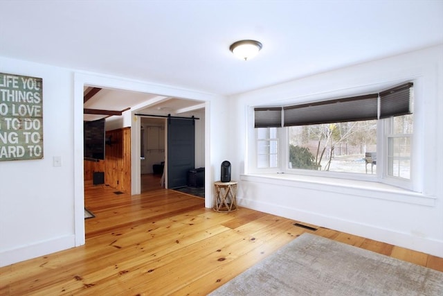 unfurnished room with a barn door and hardwood / wood-style floors