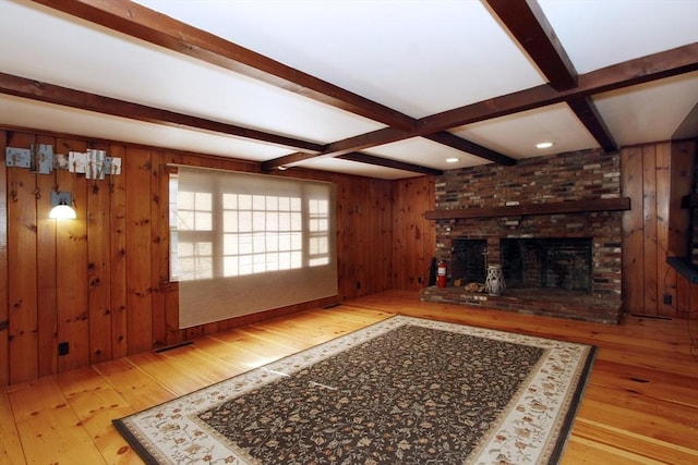 unfurnished living room featuring beamed ceiling, a fireplace, light hardwood / wood-style floors, and wood walls