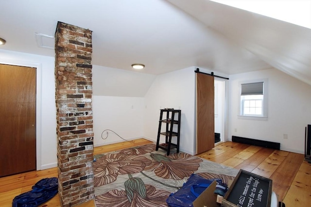 bonus room with hardwood / wood-style flooring, a barn door, and vaulted ceiling