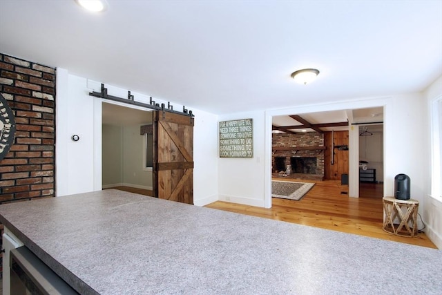 interior space with wood-type flooring, a barn door, and a brick fireplace