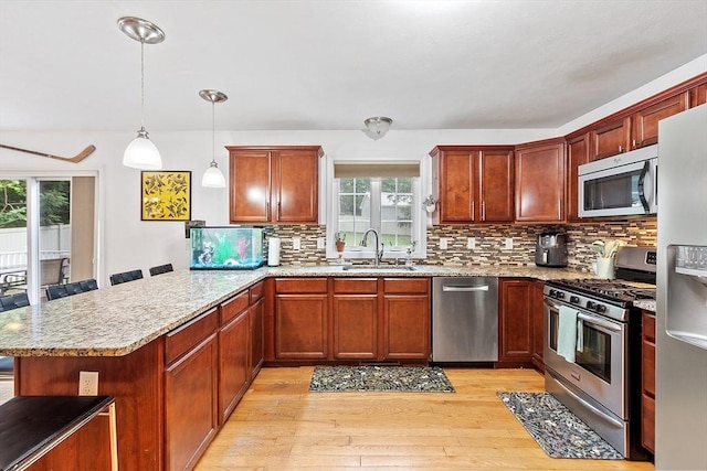 38 Phyllis Ln, Greenfield, MA 01301 - kitchen with stainless steel appliances, a sink, a peninsula, light wood-style floors, and tasteful backsplash