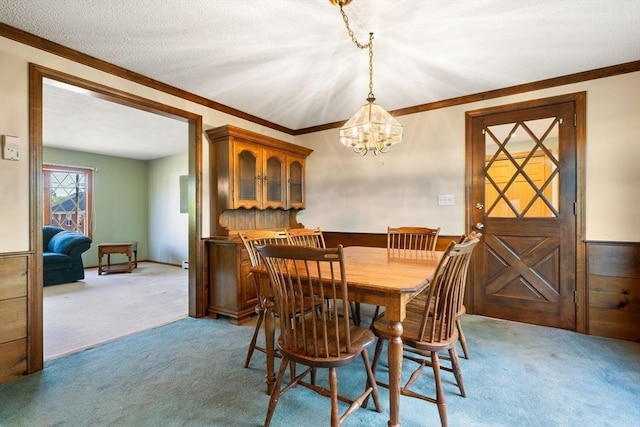 dining room featuring light colored carpet, ornamental molding, a chandelier, and a wainscoted wall