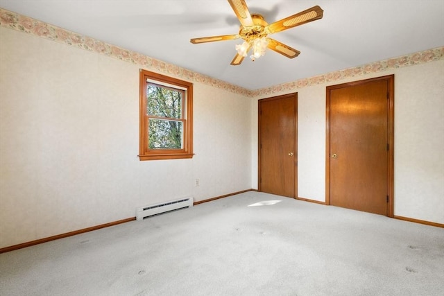 unfurnished bedroom featuring a baseboard radiator, carpet floors, two closets, and baseboards