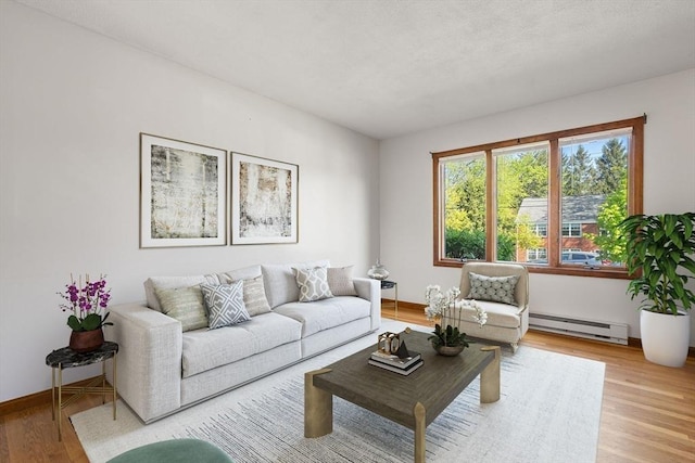 living area featuring a baseboard heating unit, light wood-type flooring, and baseboards