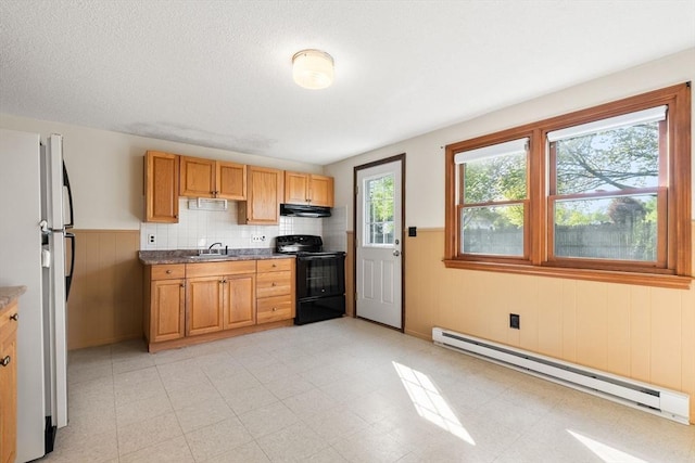kitchen featuring black range with electric cooktop, baseboard heating, freestanding refrigerator, under cabinet range hood, and a sink
