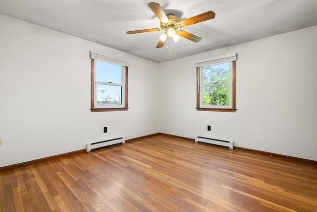 empty room featuring baseboard heating, light wood-style flooring, ceiling fan, and baseboards