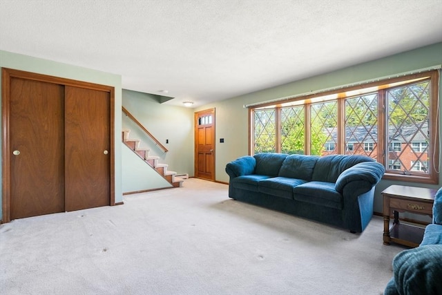 carpeted living room with healthy amount of natural light, stairway, a baseboard heating unit, and a textured ceiling