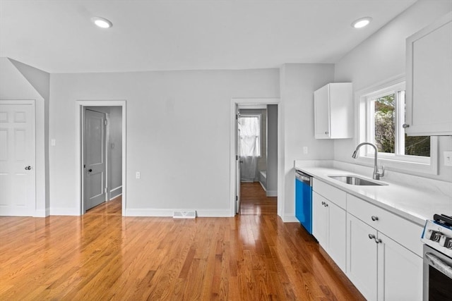 kitchen featuring a sink, dishwashing machine, gas stove, light countertops, and white cabinetry