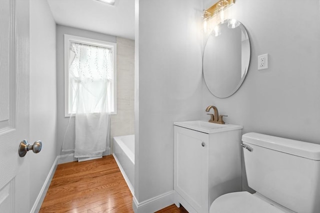 full bath featuring toilet, wood finished floors, baseboards, and vanity