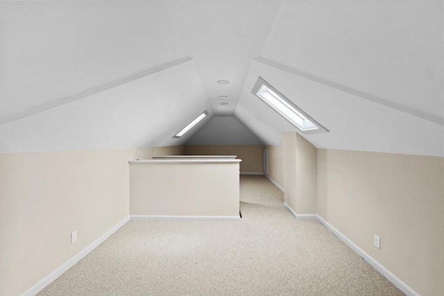additional living space featuring a skylight, lofted ceiling, carpet floors, and baseboards