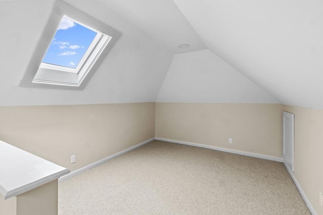additional living space with light colored carpet, lofted ceiling, baseboards, and a skylight