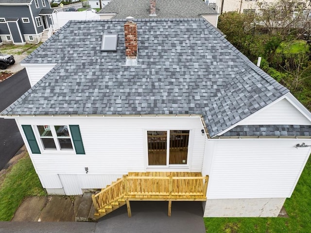 rear view of house with a shingled roof and stairs