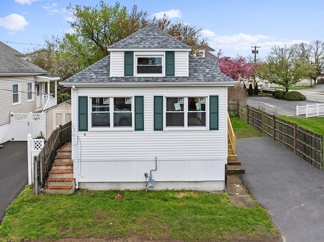 view of front of house featuring a fenced backyard and a shingled roof