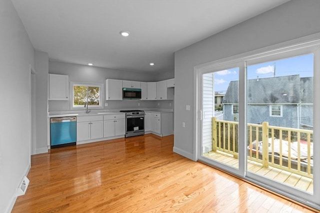 kitchen with dishwasher, black microwave, gas stove, a sink, and light wood-type flooring
