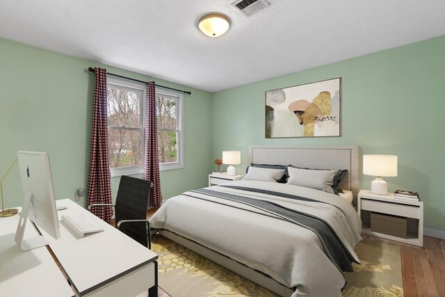 bedroom with baseboards, wood finished floors, and visible vents