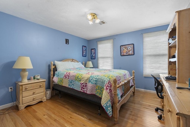 bedroom featuring baseboards, wood finished floors, and visible vents