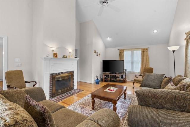 living room featuring a ceiling fan, visible vents, a brick fireplace, light wood-type flooring, and high vaulted ceiling