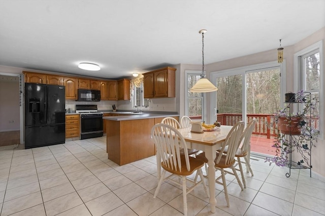 kitchen featuring brown cabinetry, a peninsula, light tile patterned flooring, light countertops, and black appliances