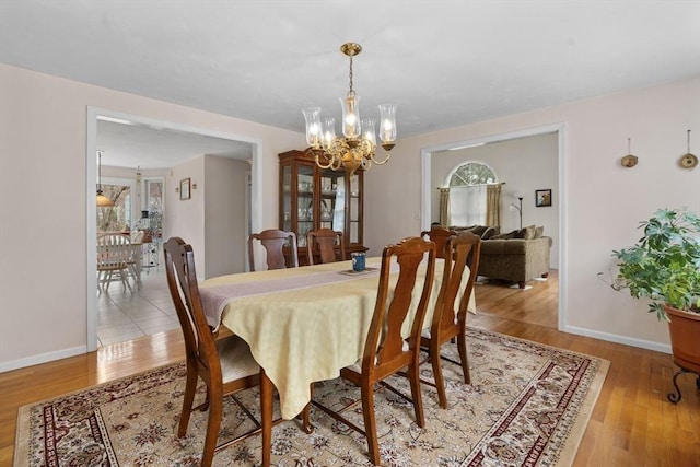 dining area with baseboards, wood finished floors, and a notable chandelier