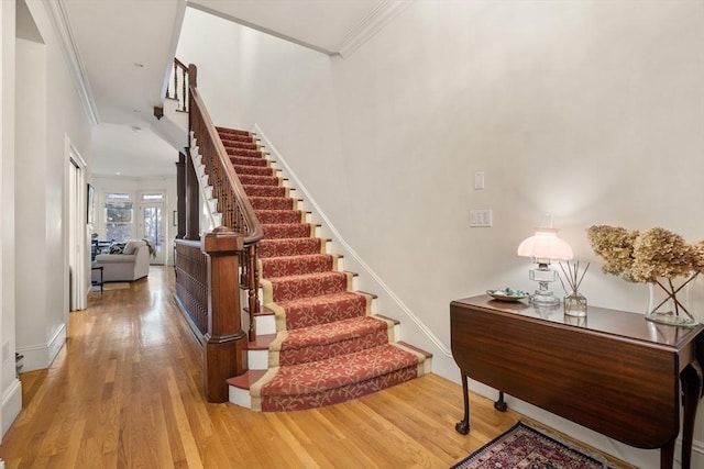 stairway featuring baseboards, ornamental molding, and wood finished floors