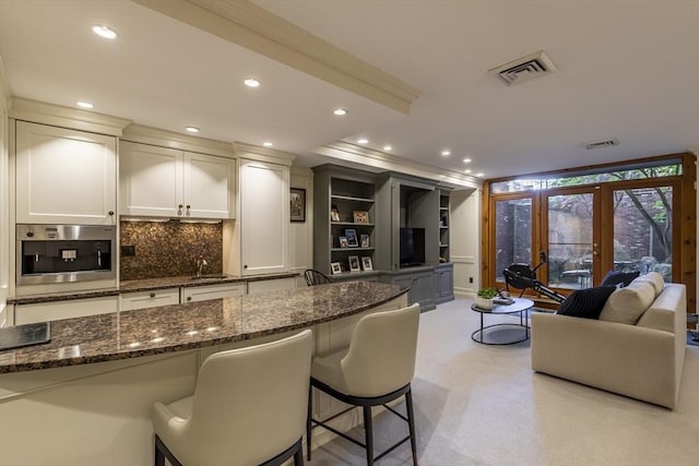 bar featuring decorative backsplash, visible vents, french doors, and stainless steel oven