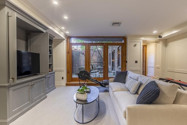 living area featuring light colored carpet, visible vents, a decorative wall, and recessed lighting