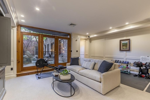 living area featuring light colored carpet, visible vents, a decorative wall, and recessed lighting