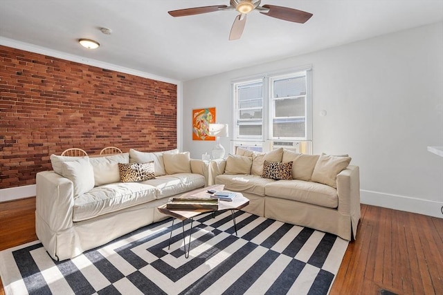 living area with hardwood / wood-style flooring, a ceiling fan, cooling unit, brick wall, and baseboards