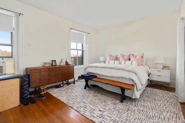 bedroom with multiple windows, baseboards, and hardwood / wood-style floors