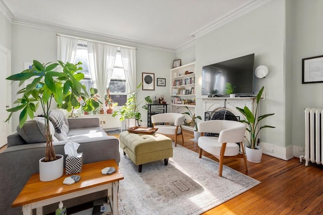 living room featuring radiator heating unit, a fireplace, crown molding, and wood finished floors