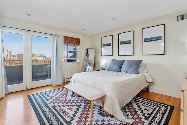 bedroom featuring baseboard heating, light wood-style flooring, baseboards, visible vents, and access to exterior
