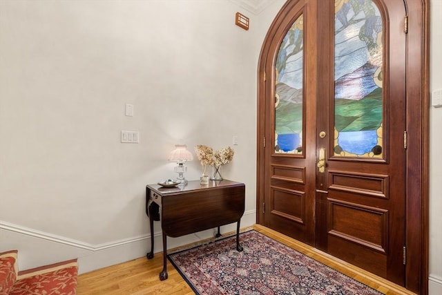 entrance foyer with french doors, light wood-style floors, baseboards, and arched walkways