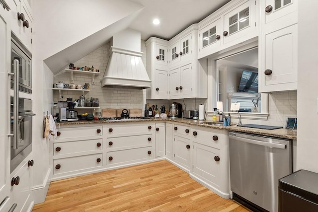 kitchen featuring premium range hood, backsplash, a sink, and appliances with stainless steel finishes