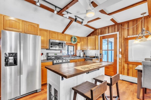 kitchen with sink, wooden counters, decorative light fixtures, vaulted ceiling, and stainless steel appliances