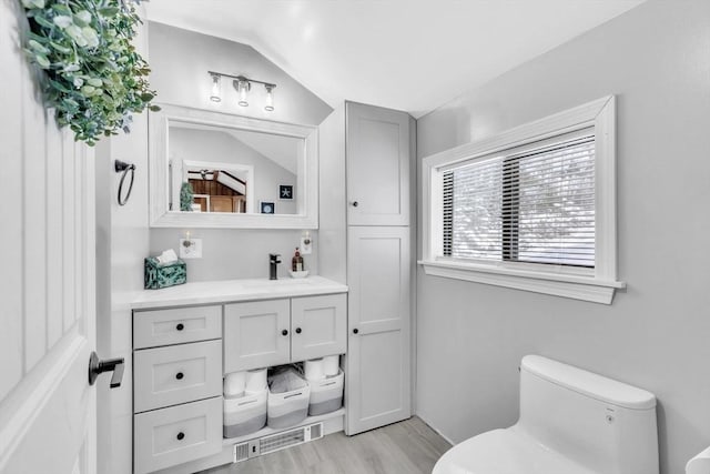 bathroom with lofted ceiling, vanity, hardwood / wood-style floors, and toilet