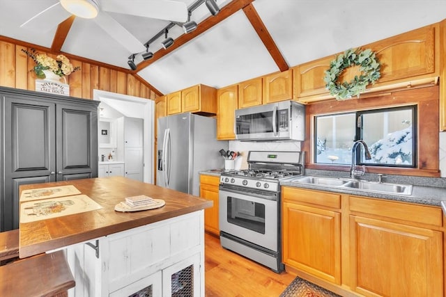 kitchen featuring sink, vaulted ceiling, appliances with stainless steel finishes, light hardwood / wood-style floors, and decorative backsplash