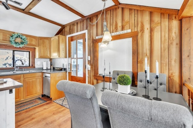 dining room featuring wooden walls, sink, light hardwood / wood-style flooring, and vaulted ceiling with beams