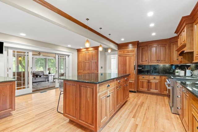 9 Twig Rush Ln, West Newbury, MA 01985 - kitchen featuring premium appliances, a kitchen island, brown cabinetry, light wood finished floors, and a breakfast bar area