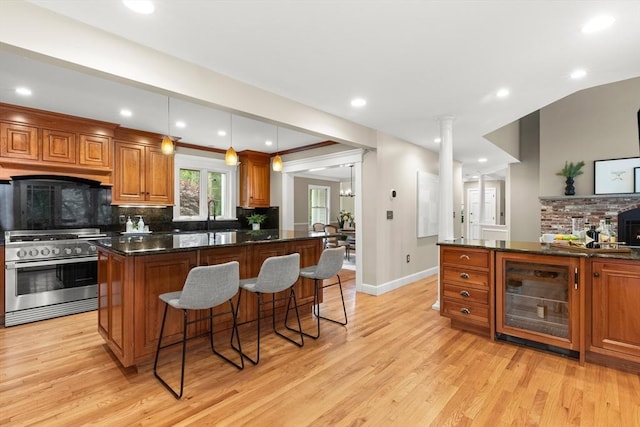 9 Twig Rush Ln, West Newbury, MA 01985 - kitchen with stainless steel gas range oven, wine cooler, ornate columns, a breakfast bar, and light wood-style flooring