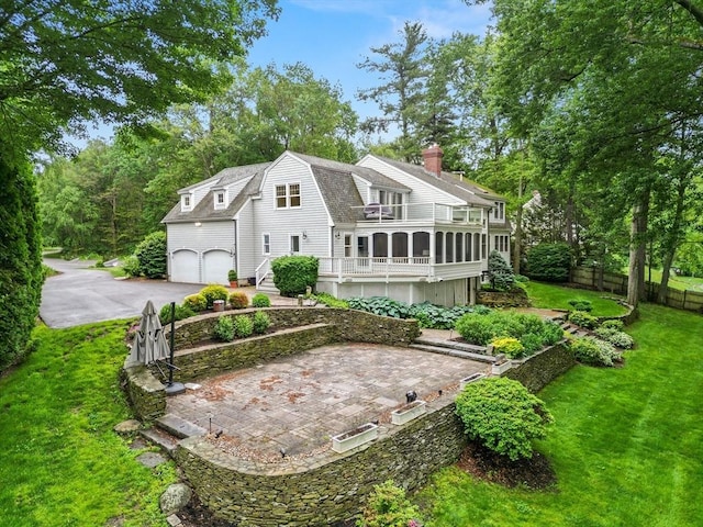 9 Twig Rush Ln, West Newbury, MA 01985 - back of property featuring a gambrel roof, roof with shingles, asphalt driveway, a sunroom, and a chimney