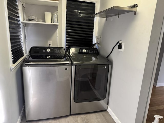 laundry area with washer and clothes dryer, baseboards, and light wood finished floors