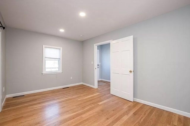 empty room featuring baseboards, light wood finished floors, and recessed lighting